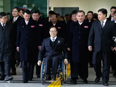 Direktur Komite Paralimpiade Pyeongchang 2018, Lim Chan-kyu (tengah) mengawal delegasi Korea Utara saat mereka tiba di Kantor Transit Korea, dekat Zona Demiliterisasi, Paju, Korea Selatan, Rabu (7/3). (Ahn Young-joon/POOL/AFP)