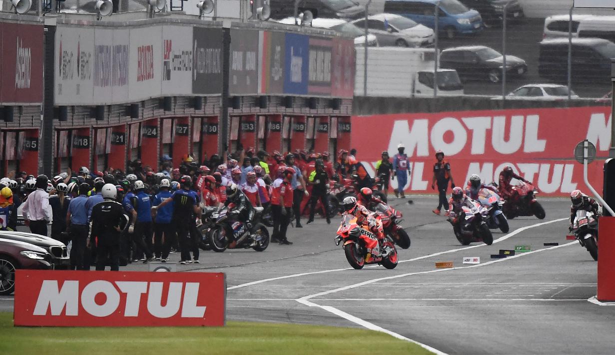 Para pembalap menuju pit untuk mengganti ban motornya saat hujan mengguyur pada lap pertama MotoGP Jepang 2023 di Sirkuit Motegi, Minggu (1/10/2023) siang WIB. (AFP/Toshifumi Kitamura)