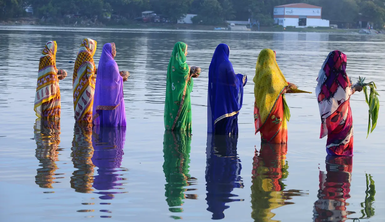 Sejumlah perempuan Hindu India membawa sesajen ketika berdoa pada matahari di tepi Danau Hussain Sagar di Hyderabad saat Festival Chhath untuk memuja dewa matahari, Selasa (17/11). (AFP PHOTO/NOAH Seelam)