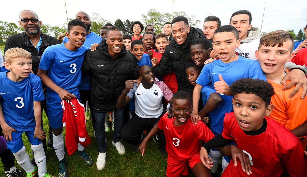 Pemain Timnas Prancis, Anthony Martial dan Patrice Evra, berfoto bersama pemain muda Les Ulis, (23/5/2016). Les Ulis adalah klub masa kecil keduanya. (AFP/Franck Fife) 