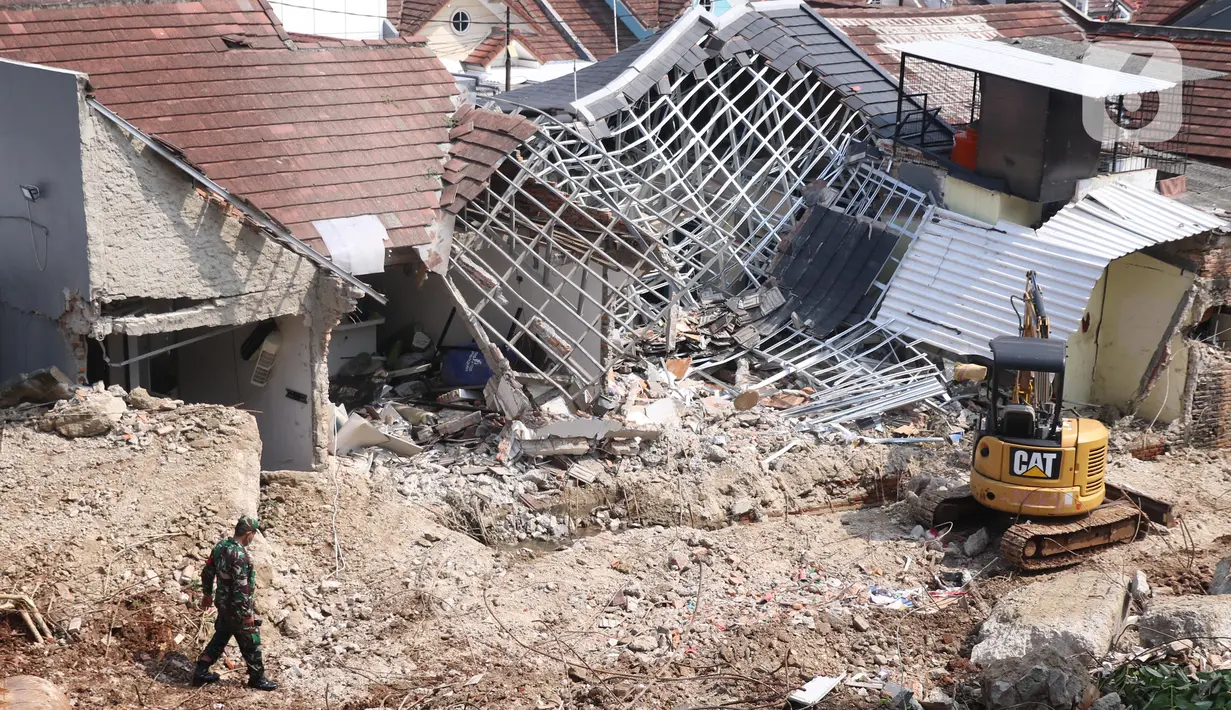 Petugas berada dekat rumah yang hancur tertimpa tanah longsor di Perumahan Nerada Estate Ciputat, Tangerang Selatan, Sabtu (12/6/2021). Tidak ada korban jiwa dalam peristiwa longsor yang menimpa sejumlah rumah akibat hujan deras yang terus menerus di kawasan tersebut. (Liputan6.com/Angga Yuniar)