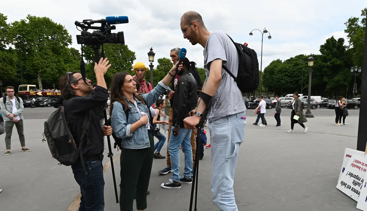 Wartawan saat mewawancarai Brahim Takioullah yang memiliki tinggi tubuh 2 meter 46 centimeter saat berkumpul dengan orang-orang tertinggi dunia di Champs-Elysees Avenue di Paris, Prancis (14/6/2019). (AFP Photo/Dominique Faget)