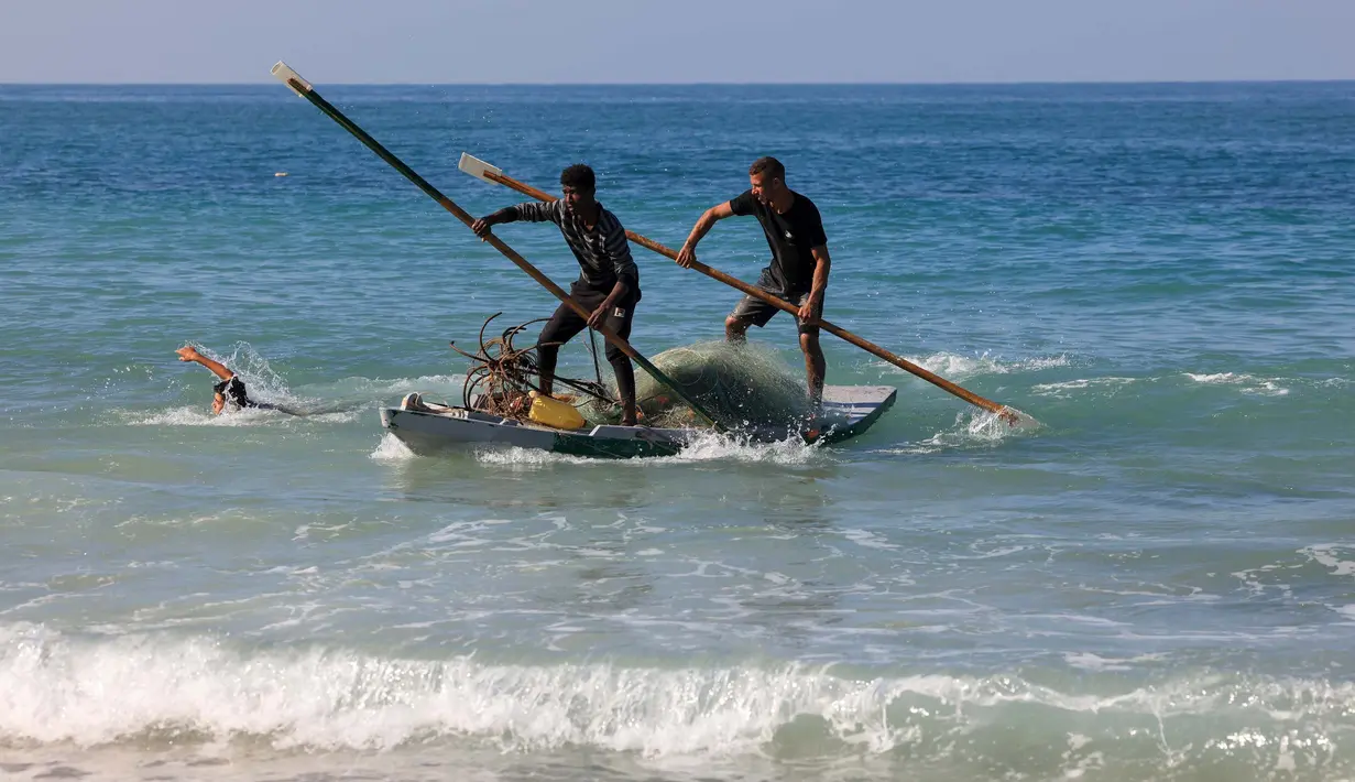 Nelayan Palestina mendayung di pantai Deir el-Balah, di Jalur Gaza Tengah pada 30 November 2023. (Mahmud Hams/AFP)