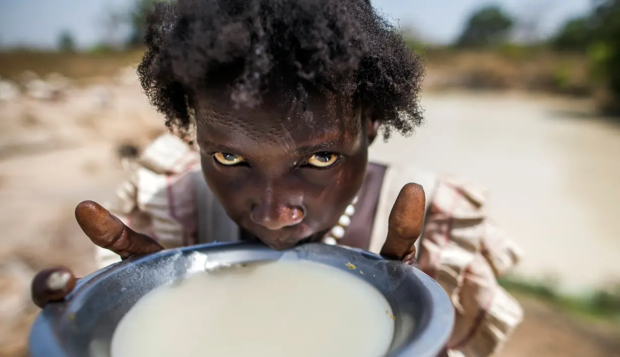 Seorang wanita bernama Alissa Lual minum air dari sebuah kubangan di lokasi proyek pembangunan jalan di dekat penampungan, Sudan Selatan (22/11). (AFP Photo/Albert Gonzalez Farran)