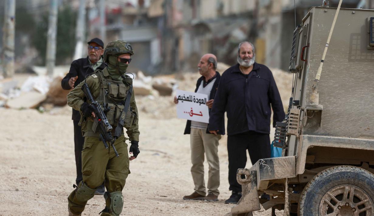 Menteri Luar Negeri Indonesia bersama Mesir, Yordania, Pakistan, Arab Saudi, Turki, Uni Emirat Arab, dan Qatar telah mengeluarkan pernyataan mengutuk sekeras-kerasnya keputusan dan langkah Israel yang bertujuan memberlakukan kedaulatan yang melanggar hukum, memperkokoh aktivitas permukiman, serta menerapkan realitas hukum dan administratif baru di Tepi Barat yang diduduki, sehingga mempercepat upaya aneksasi dan pengusiran rakyat Palestina. Tampak dalam foto, seorang tentara Israel berjalan di dekat warga Palestina yang berdemonstrasi setelah memblokir pintu masuk kamp pengungsi Palestina Nur Shams di Tepi Barat yang diduduki pada Senin 9 Februari 2026. (Jaafar ASHTIYEH/AFP)