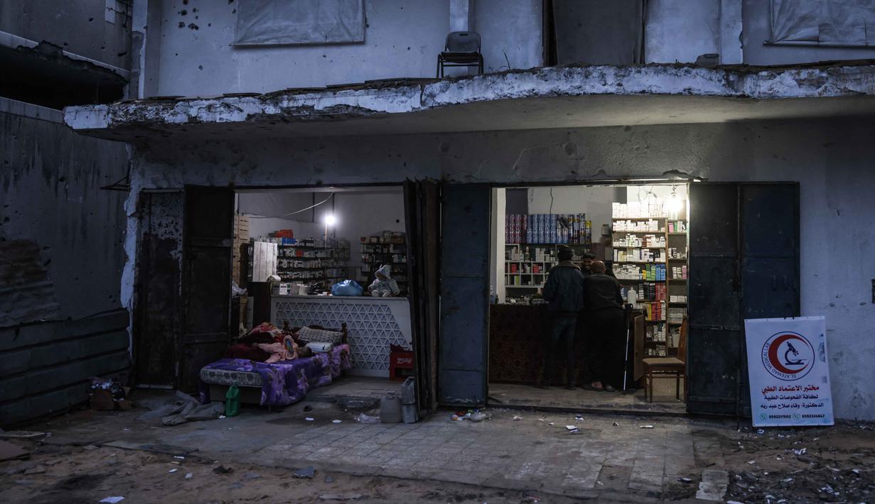 Meski mendapati rumah mereka telah rata dengan tanah, warga tetap kembali ke lingkungan Al-Saftawi di kota Jabalia, Jalur Gaza utara. Tampak dalam foto, para pria berdiri di sebuah konter apotek di lingkungan Al-Saftawi, sebelah barat kota Jabalia di Jalur Gaza utara pada Rabu 10 Desember 2025. (BASHAR TALEB/AFP)