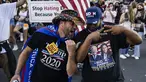 Seorang pendukung Presiden Donald Trump (kiri) dan seorang pendukung mantan Wakil Presiden Joe Biden (kanan) menari bersama saat yang lain merayakan hasil Pilpres Amerika Serikat di Black Lives Matter Plaza, dekat Gedung Putih di Washington pada Minggu (8/11/2020). (Samuel Corum/Getty Images/AFP)