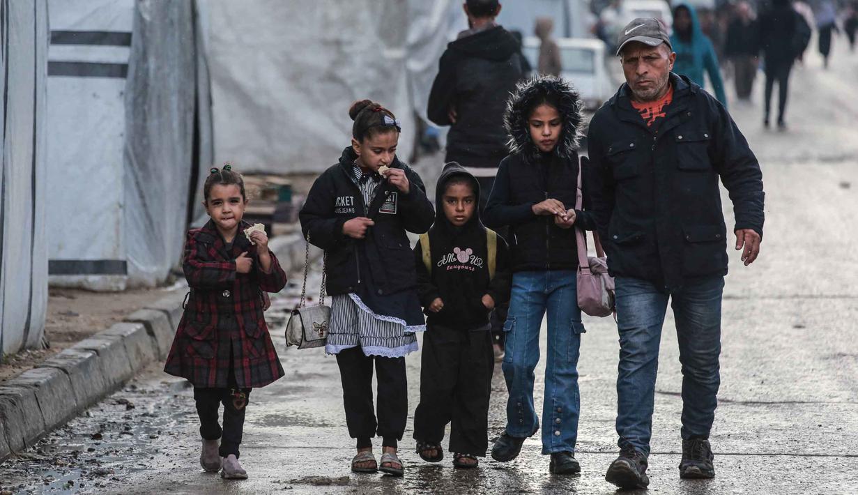Kembalinya anak-anak ke sekolah merupakan momen penting dalam upaya memulihkan kehidupan di Gaza di tengah gencatan senjata, meskipun tantangan yang dihadapi masih sangat besar. Tampak dalam foto, seorang pria mengantar anak-anaknya ke sekolah di Deir al-Balah, di Jalur Gaza tengah, pada 10 Desember 2025. (BASHAR TALEB/AFP)