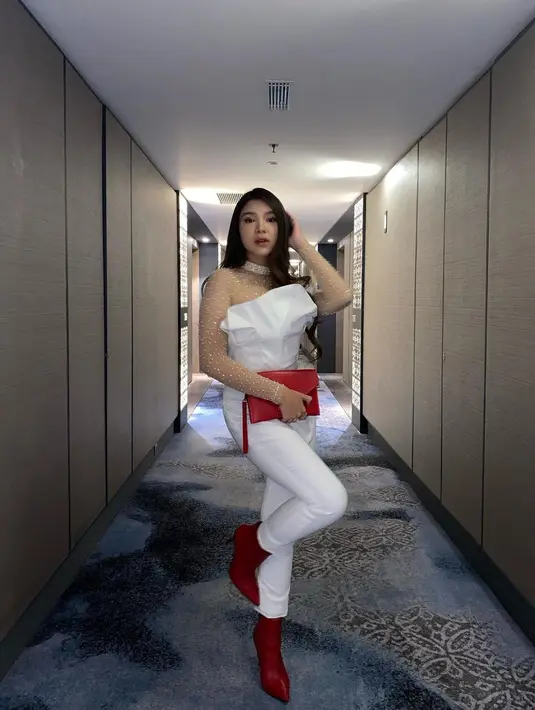 Tampil seksi dengan busana putih, Tiara Andini mengenakan atasan asymetric off shoulder yang memiliki lengan transparan bertabur beads. Boots dan clutch merah yang ia kenakan membuatnya tampil menonjol.