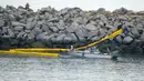 Sebuah kapal menyebarkan penghalang setelah tumpahan minyak di Pantai Newport, California, Amerika Serikat, 4 Oktober 2021. Tumpahan minyak menyebabkan ikan dan burung mati berserakan. (AP Photo/Ringo H.W. Chiu)