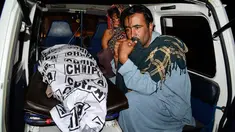 Dua pria berada di dekat anggota keluarganya yang tewas akibat aksi bom bunuh diri di Quetta, Pakistan, (13/7). Ledakan bom bunuh diri terjadi saat kampanye menjelang pemilihan umum 25 Juli mendatang. (AP Photo/Arshad Butt)