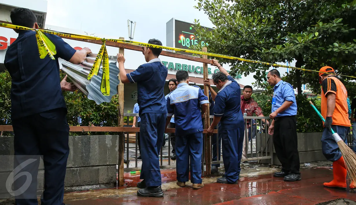 Petugas membongkar seng-seng yang menghiasi depan gerai Starbucks, Jalan MH Thamrin, Jakarta, Jumat (15/1). Sebelumnya, pasca-ledakan pada Kamis (14/1), pihak pengelola Menara Cakrawala memagari sekeliling gedung dengan seng. (Liputan6.com/Faizal Fanani)