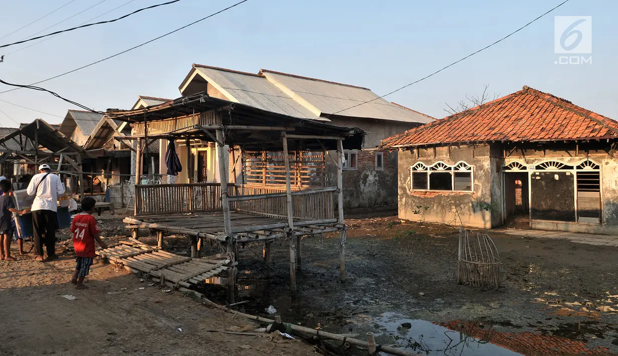 Anak-anak bermain di depan salah satu rumah yang ditinggalkan penghuni di Kampung Beting, Desa Pantai Bahagia, Muara Gembong, Kabupaten Bekasi, Jawa Barat, pada 28 Juli 2019. (merdeka.com/Iqbal S Nugroho)