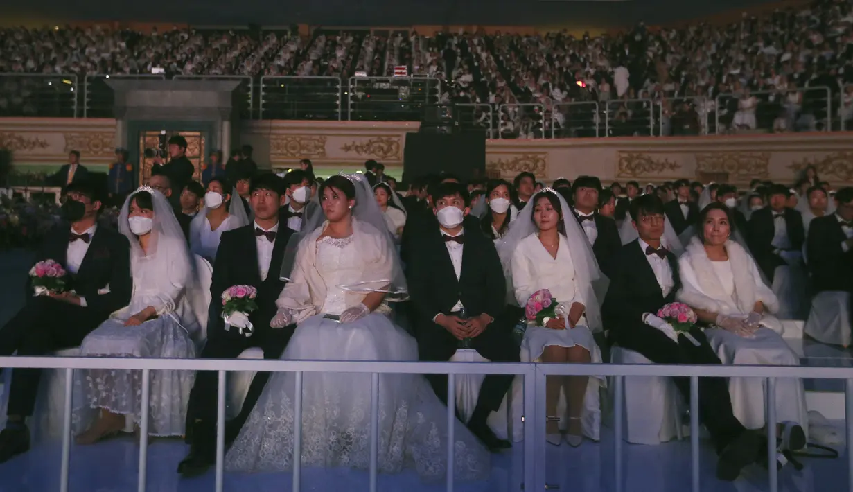 Sejumlah pasangan mengikuti kegiatan nikah massal di Cheong Shim Peace World Center di Gapyeong, Korea Selatan, Jumat, (7/2/2020). Meski memakai masker untuk mencegah virus corona, para pasangan pengantin tampak bahagia di acara tersebut. (AP Photo/Ahn Young-joon)