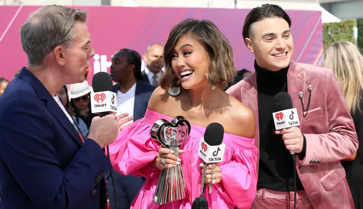 Penyanyi Agnez Mo (tengah) memegang piala iHeartRadio Music Awards 2019 di Los Angeles, California, AS, Kamis (14/3). Agnez Mo mengalahkan Bhad Bhabie, Joji, Lele Pons, Queen Naija hingga Trixie Mattel. (Phillip Faraone/Getty Images North America/AFP)