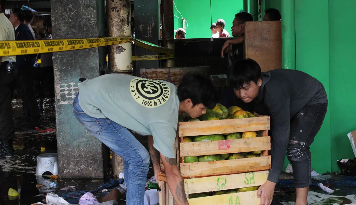 Sejumlah aparat kepolisian berjaga di lokasi dan melakukan penyelidikan untuk memastikan penyebab pasti kebakaran, sementara pihak terkait terus mendata kerugian akibat insiden tersebut. Tampak dalam foto, beberapa pedagang berupaya menyelamatkan sisa dagangannya setelah api yang membakar Pasar Induk Kramat Jati Jakarta berhasil dipadamkan pada Senin (15/12/2025). (merdeka.com/magang/Rendi Saputra)