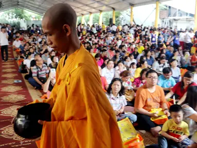 Seorang biksu berjalan di depan umat Buddha yang merayakan Hari Raya Waisak 2562 BE/2018 di Wihara Ekayana Arama, Jakarta Barat, Selasa (29/5). Puja Bakti Massal Waisak 2562 BE diikuti oleh ribuan umat Buddha. (Liputan6.com/JohanTallo)