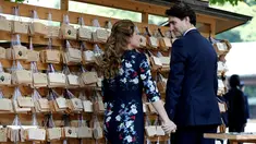  Perdana Menteri Kanada Justin Trudeau bersama istrinya Sophie Gregoire Trudeau saling pegangan tangan saat mereka mengantungkan 'Ema' atau sebuah harapan yang mereka tulis di sebuah kayu di Kuil Meiji di Tokyo, Jepang (24/5). (REUTERS/Issei Kato)