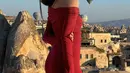 Penampilan stunning Fuji mengenakan strapless dress berwarna merah dengan detail lengan panjang, saat menyaksikan balon udara di Cappadocia. [Foto: Instagram/fuji_an]