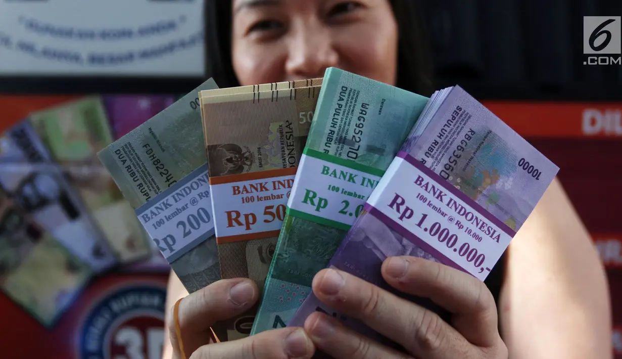 Seorang warga menunjukkan uang pecahan hasil penukaran di Lapangan IRTI Monas, Jakarta, Rabu (23/5). Bank Indonesia (BI) telah membuka layanan kas keliling bekerja sama dengan 13 bank di kawasan Monas. (Liputan6.com/Arya Manggala)