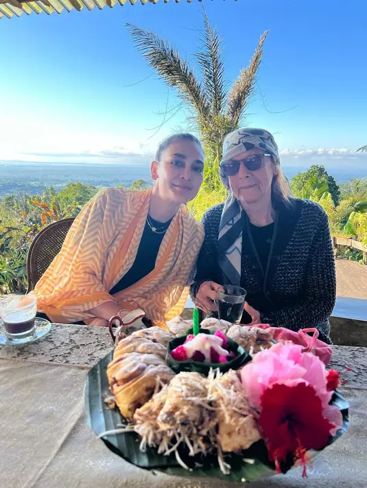 Dalam suasana kasual, Luna Maya tampil dengan outer putih dengan motif garis zigzag warna soga yang membalut dalaman hitam polos. Mempercantik penampilan, ia memakai kalung. Desa Maya tampak santai dengan atasan hitam yang dibalut sweter berwarna gelap. Ia menjadikan selendak motif abstrak sebagai penutup rambut. Menghadap kue berhias bunga dan lilin, keduanya “berpesta.” (Foto: Instagram @lunamaya)