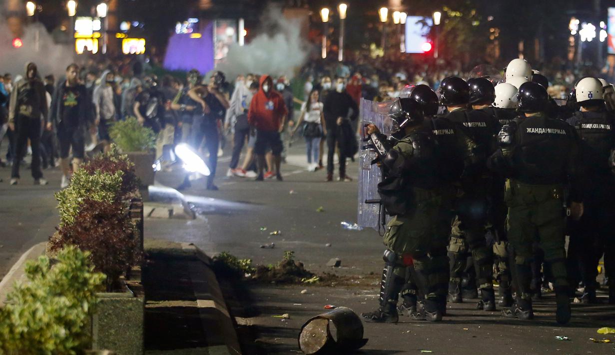 Aparat kepolisian Serbia bentrok dengan pengunjuk rasa di dekat gedung parlemen di Beograd, Selasa (7/7/2020). Ribuan pengunjuk rasa marah setelah pemerintah mengeluarkan keputusan untuk memberlakukan kembali jam malam akibat melonjaknya kasus Covid-19. (AP/Marko Drobnjakovic)