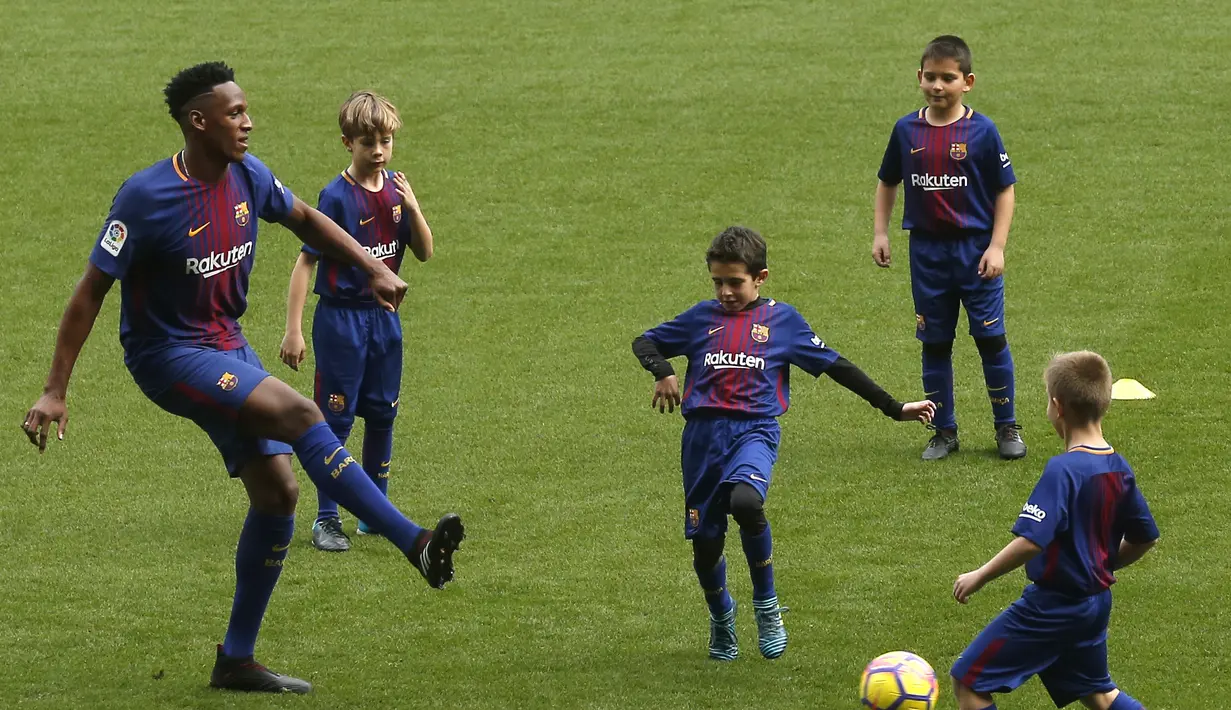Yerry Mina beraksi dengan bermain bola bersama anak-anak akademi Barcelona di Camp Nou stadium, Barcelona, (13/1/2018). Mina didatangkan Barcelona dari Palmeiras sebesar 10.5 juta pounds. (AP/Manu Fernandez)
