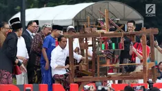 Presiden Joko Widodo mencoba alat penenun kain di Festival Sarung Indonesia 2019, Plaza Tenggara Kompleks GBK, Jakarta, Minggu (3/3). Festival ini untuk menghidupkan kesadaran generasi muda akan kekayaan budaya Indonesia. (Liputan6.com/Helmi Fithriansyah)