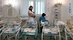 Perawat merawat bayi yang baru lahir dari skema ibu pengganti (surrogate mother) di Hotel Venice, Kiev, Ukraina, 15 Mei 2020. Bayi-bayi tersebut telantar karena orangtua mereka tidak dapat mengambil bayi-bayinya akibat lockdown selama pandemi virus corona COVID-19. (Sergei SUPINSKY/AFP)