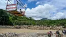 Selain untuk menyeberang, tali sling juga dipakai mengangkut hasil panen seperti durian, cabai, kopi, hingga beras menuju pasar. Tampak dalam foto, warga menggunakan tali untuk menyeberangi sungai setelah banjir bandang yang menghancurkan desa-desa di sekitarnya di Ketol, provinsi Aceh, pada Selasa 6 Januari 2026. (CHAIDEER MAHYUDDIN/AFP)