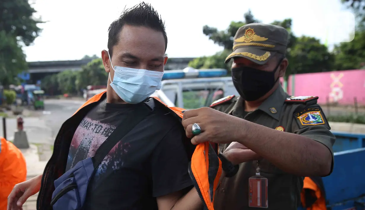 <p>Petugas Satpol PP memakaikan rompi kepada pelanggar saat razia masker di depan Stasiun Klender, Jakarta, Selasa (10/5/2022). Pemerintah memastikan akan terus memperpanjang masa pemberlakuan pembatasan kegiatan masyarakat (PPKM) se-Indonesia hingga waktu yang belum ditentukan. (Liputan6.com/Faizal Fanani)</p>
