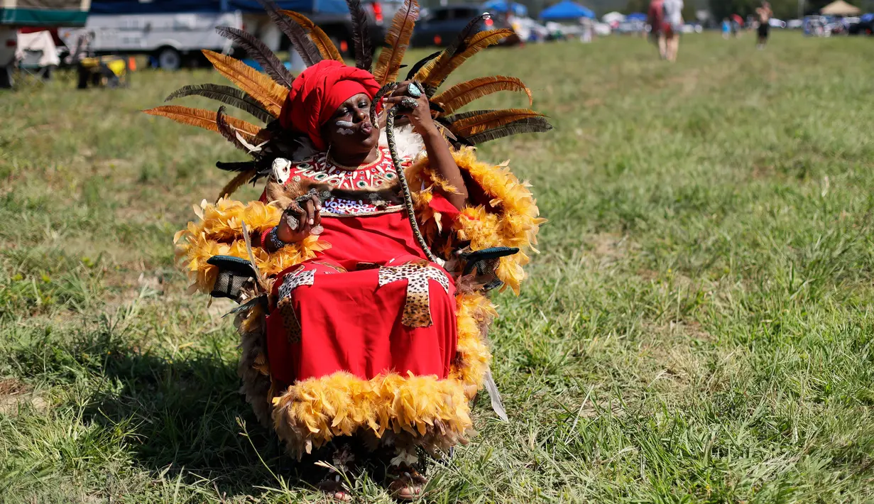 Wanita berkostum “The Voodo Bone Lady” dari New Orleans duduk sambil memegang ular untuk menyaksikan gerhana matahari di Hopkinsville, Kentucky, Senin (21/8). Gerhana matahari total diperkirakan bisa dinikmati selama 600 tahun sekali.  (Mark Humphrey/AP)
