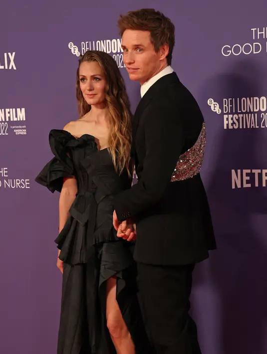 <p>Aktor Inggris Eddie Redmayne (kanan) dan istrinya Hannah Bagshawe berpose untuk fotografer saat tiba untuk pemutaran perdana film 'The Good Nurse' pada acara London Film Festival di London, Inggris, 10 Oktober 2022. Sama seperti Eddie Redmayne, Hannah juga mengenakan gaun hitam unik karya Alexander McQueen. (ISABEL INFANTES/AFP)</p>