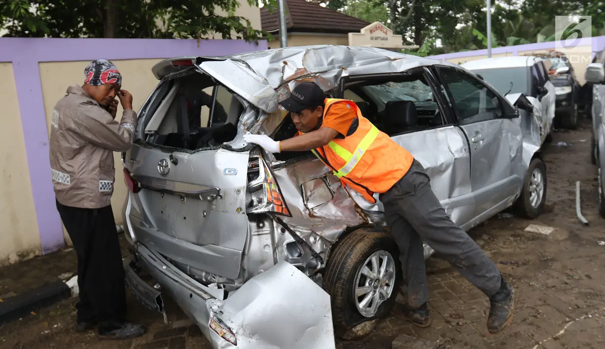 Petugas makukan evakuasi mobil yang rusak akibat terjangan Tsunami Selat Sunda di Terminal Carita, Banten, Selasa (25/12). Di terminal ini pemilik mobil dapat mengambilnya yang disertai dengan STNK. (Liputan6.com/Angga Yuniar)