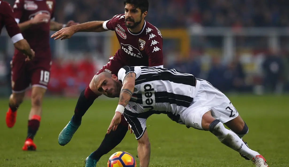 Gelandang Juventus, Stefano Sturaro, terjatuh saat berusaha melewati bek Torino, Luca Rossettini dalam laga pekan ke-16 Serie A 2016-2017 di Stadion Olimpico Grande Torino, Minggu (11/12/2016). (AFP/Marco Bertorello)