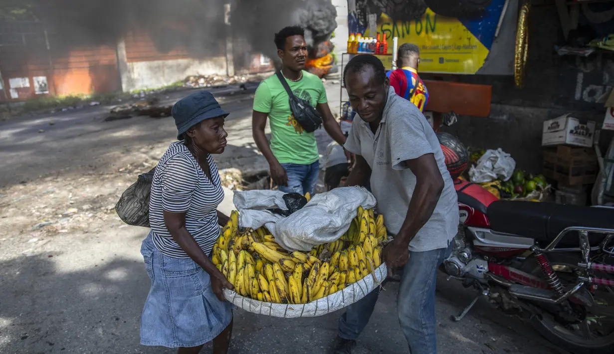 Pedagang memindahkan barang-barangnya saat protes menuntut pembebasan orang-orang yang diculik di Port-au-Prince, Haiti, 25 November 2021. Haiti mengalami peningkatan kasus penculikan terkait geng dan banyak yang menuntut uang tebusan. (AP Photo/Odelyn Joseph)