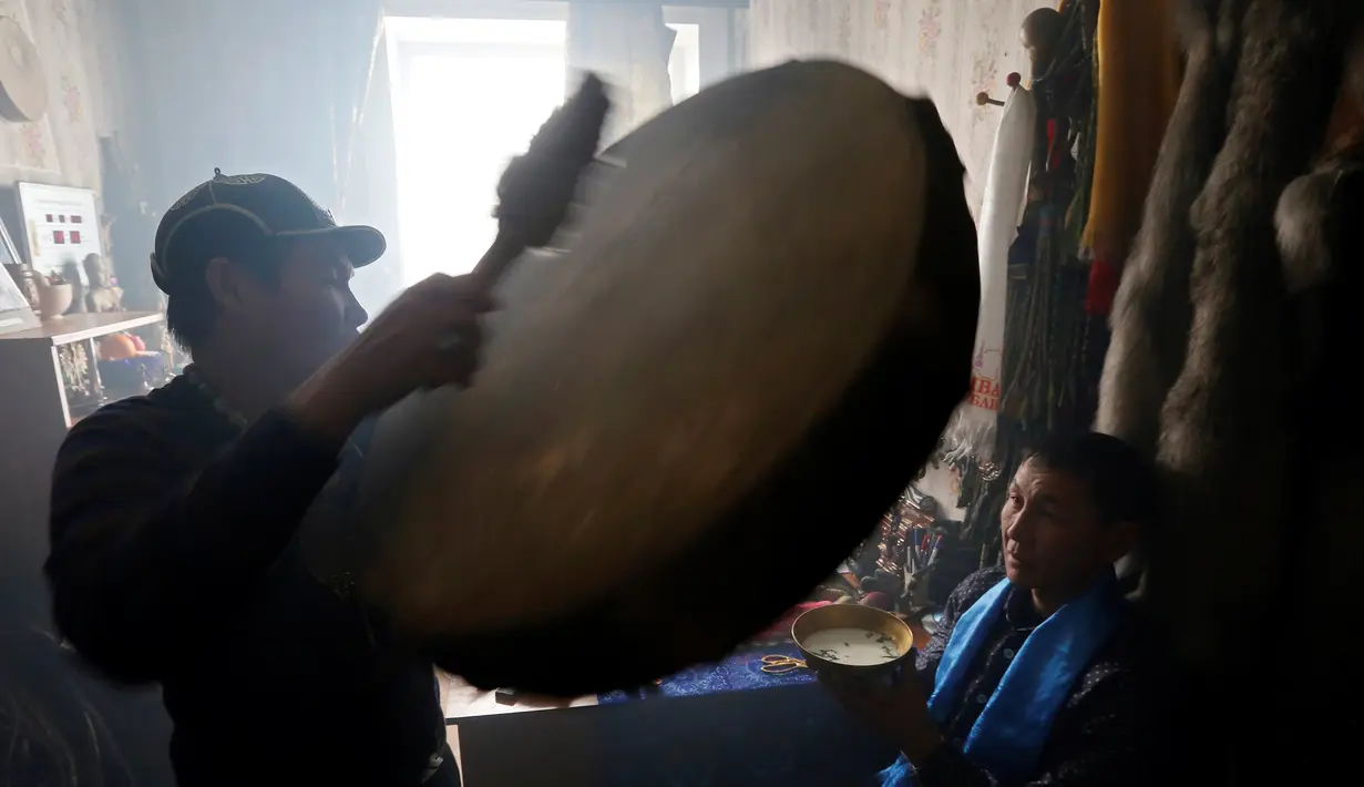 Seorang dukun menabuh alat musik saat mengusir roh jahat di kediaman pelanggannya di Kota Kyzyl, Tuva, Siberia, Rusia, (3 /11). Dukun-dukun kaum nomaden tersebut diyakini juga dapat menyembuhkan penyakit dan meramal masa depan. (REUTERS/Ilya Naymushin)
