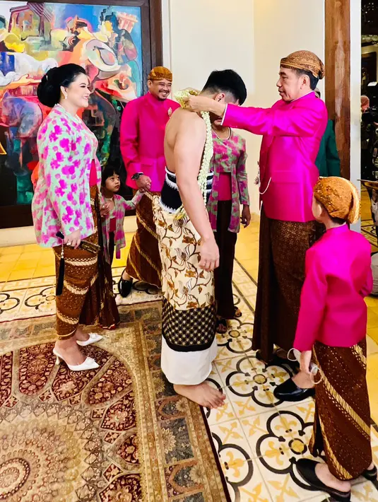 <p>Presiden Joko Widodo atau Jokowi (kanan) memasangkan rangkaian bunga terhadap sang anak Kaesang Pangarep jelang pernikahannya di kediaman, Sumber, Kota Surakarta, Jawa Tengah, Jumat (9/12/2022). "Kita sebagai orangtua mengharapkan juga mendoakan agar keluarga Mas Kaesang dan Mbak Erina ke depan bisa menjadi keluarga yang sakinah, mawaddah, warahmah," kata Jokowi. (Tim Media Pernikahan Kaesang-Erina)</p>