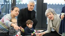 Ekspresi Perdana Menteri Inggris Theresa May saat bermain dengan bayi di pusat kesehatan di London, Inggris, Kamis (22/11). Theresa menjadi PM Inggris setelah David Cameron, PM sebelumnya, mengundurkan diri akibat Brexit. (Andrew Matthews/Pool via AP)