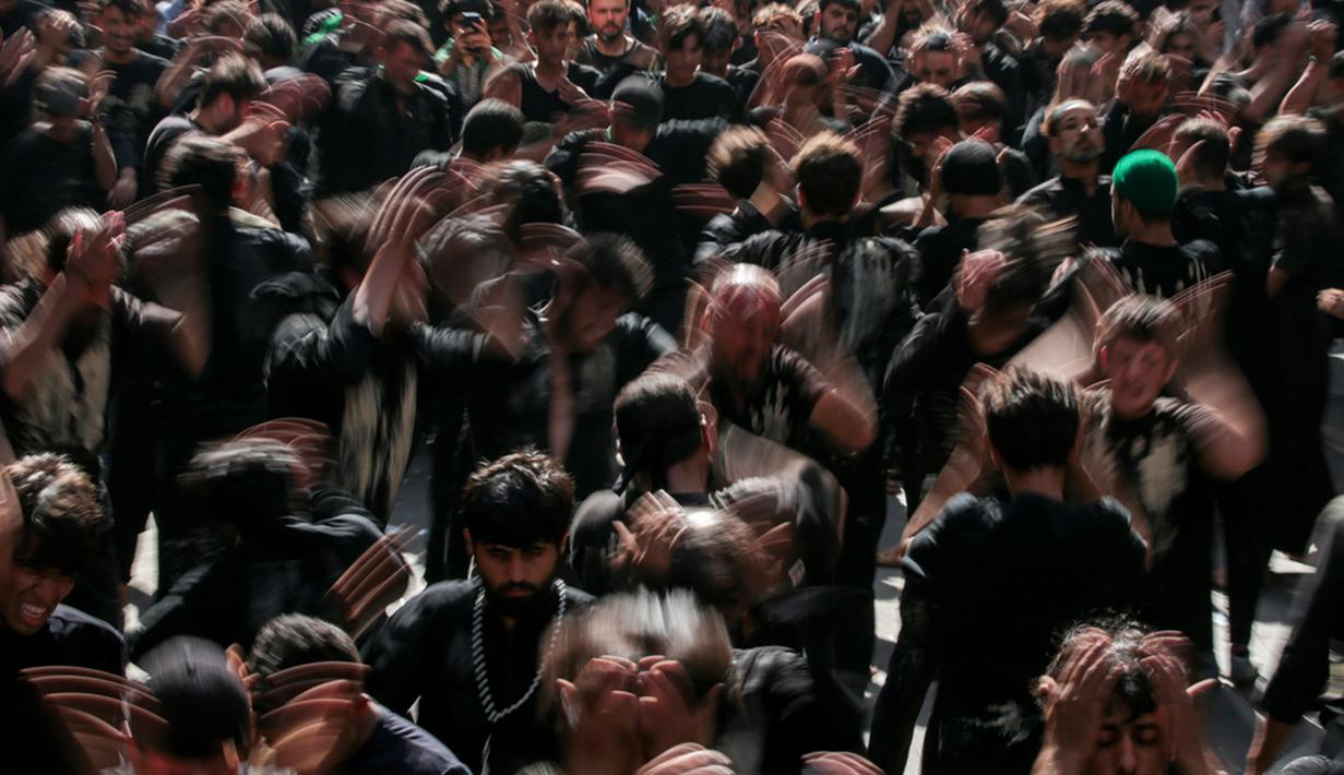 Dengan mengenakan pakaian berwarna hitam yang sengaja dikotori dan dikoyak, rombongan umat Syiah serentak memukul dada. (AP Photo/Anmar Khalil)