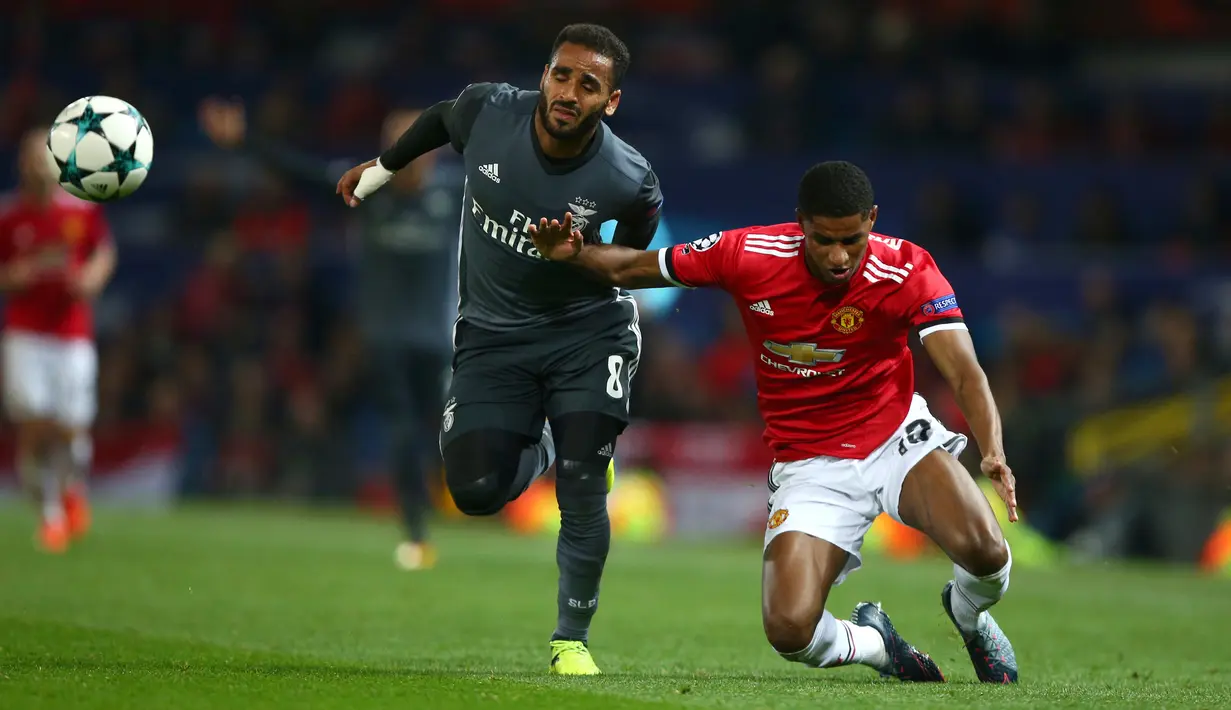Pemain Manchester United, Marcus Rashford berebut bola dengan pemain Benfica, Douglas pada laga Grup A Liga Champions di Old Trafford, Rabu (1/11) dini hari. MU sukses memetik kemenangan 2-0. (AP Photo/Dave Thompson)