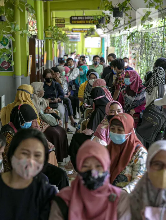 Sejumlah tenaga pendidik duduk menunggu untuk vaksin COVID-19 di SMP 216, Jakarta Pusat, Selasa (6/4/2021). Pemerintah akan mengatur kembali pemberian vaksin Covid-19 kepada masyarakat karena terbatasnya pasokan vaksin saat ini. (Liputan6.com/Faizal Fanani)