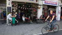 Pengunjung makan di luar di sebuah restoran di Tel Aviv, Israel pada Rabu (27/5/2020). Setelah lebih dari dua bulan ditutup untuk membendung penularan virus corona, restoran hingga kafe di Israel diizinkan dibuka kembali hari Rabu, 27 Mei. (AP Photo/Sebastian Scheiner)