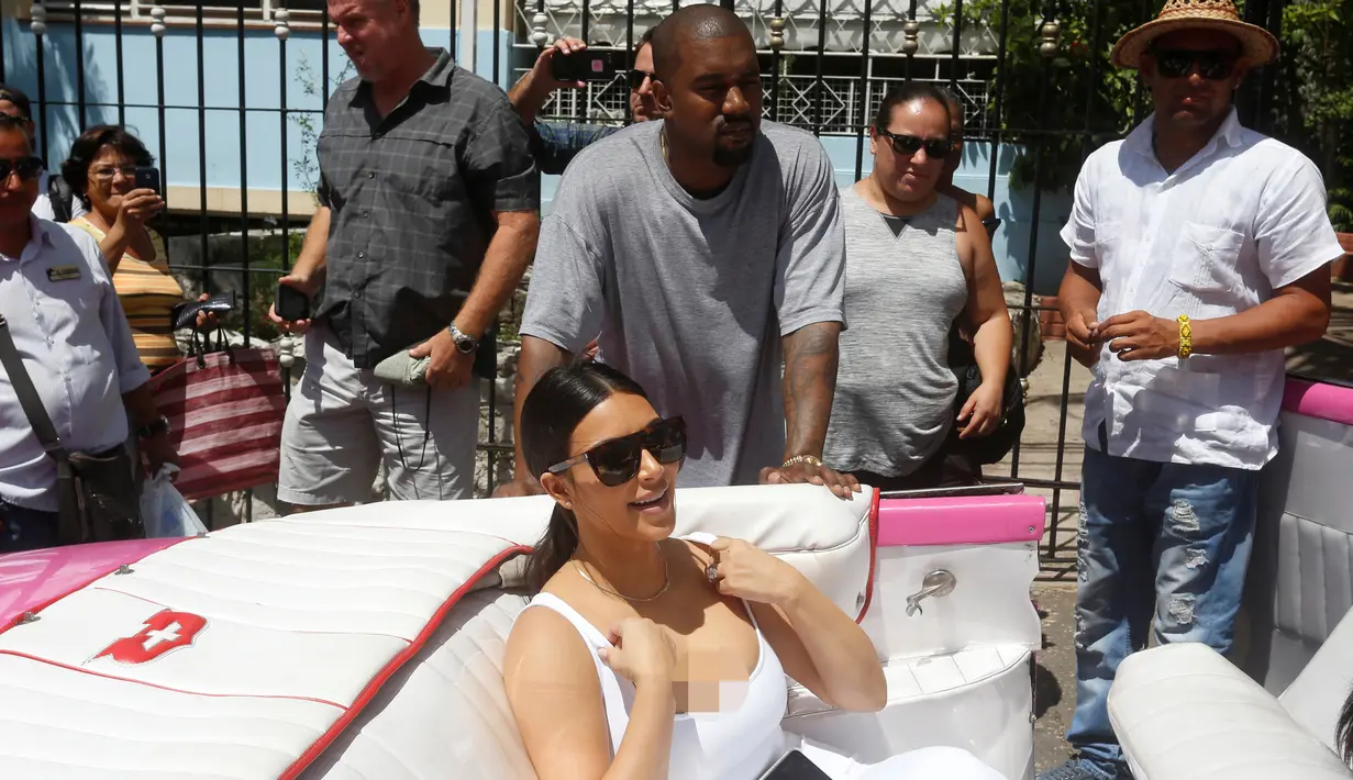 Musisi Kanye West menemani istrinya Kim Kardashian yang berada di mobil kuno setelah meninggalkan sebuah restoran di Havana, Cuba, 5 Mei 2016. Kim bersama seluruh anggota keluarganya ke Kuba untuk syuting serial reality show miliknya. (REUTERS / Stringer)