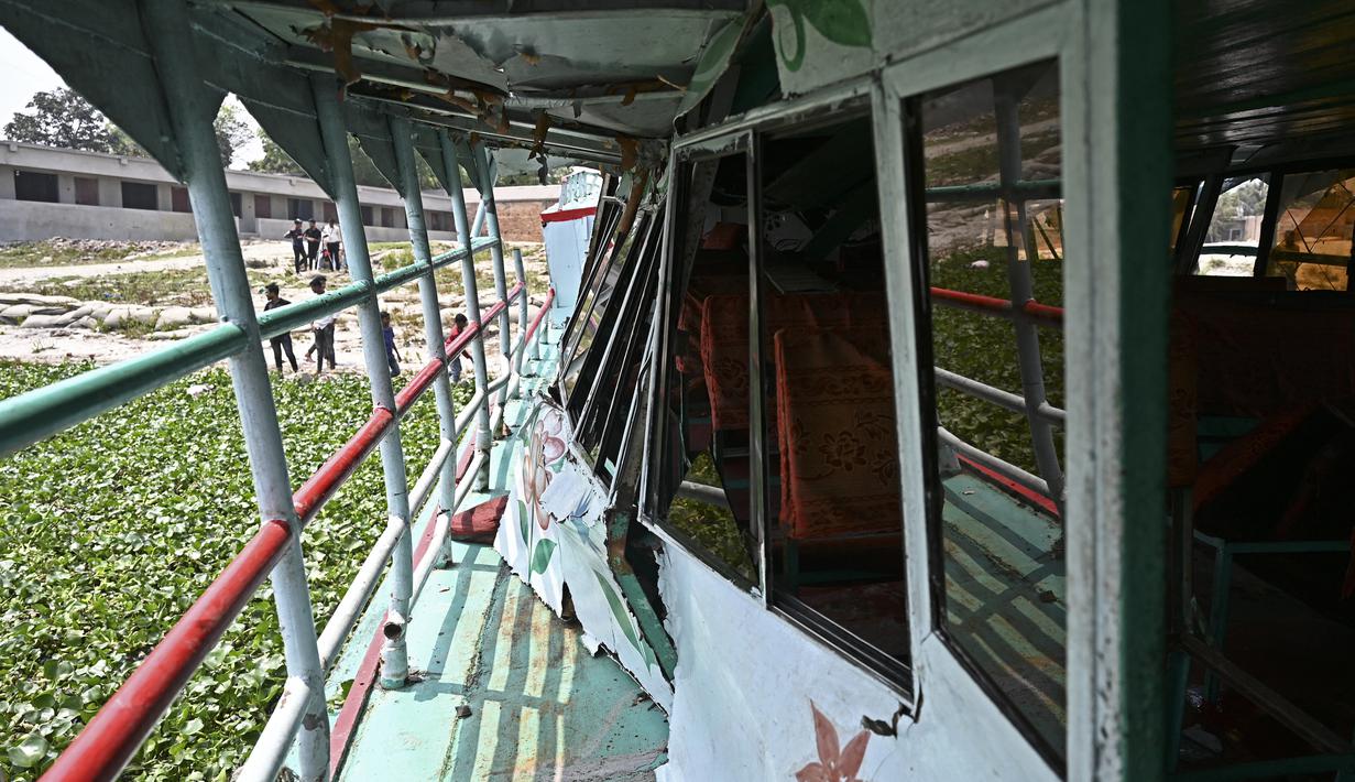 Warga berdiri di dekat bagian yang rusak dari feri yang diselamatkan setelah kecelakaan di Sungai Shitalakshya di Narayanganj, Bangladesh (21/3/2022). Setidaknya enam mayat ditemukan dan 20 orang masih hilang setelah sebuah feri terbalik di sungai Shitalakkhya. (AFP/Munir uz Zaman)