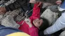 Seorang gadis menangis saat anggota Syrian Civil Defence atau White Helmets berusaha menyelamatkannya dari timbunan puing bangunan usai serangan udara pasukan pemerintah di Desa Tal Mardikh, Provinsi Idlib, Suriah, Kamis (19/12/2019). Pasukan Suriah kian intens menyerang Idlib. (Omar HAJ KADOUR/AFP)