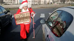 Remi Le Calvez, menghampiri sebuah mobil saat ia mencari tumpangan dengan mengenakan kostum Santa Claus di Paris, Prancis, Selasa (6/12). Remi membagi pengalaman dari perjalanannya kepada orang-orang lewat blog dan Facebooknya. (Reuters/Benoit Tessier)