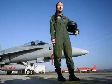 Pilot jet tempur Swiss, Fanny Chollet berpose di dekat pesawat F/A-18 di Pangkalan Udara Payerne, Swiss, (19/12). Fanny Chollet 28 tahun yang dijuluki 'Shotty' merupakan pilot jet tempur perempuan pertama Swiss. (AFP Photo/Fabrice Coffrini)