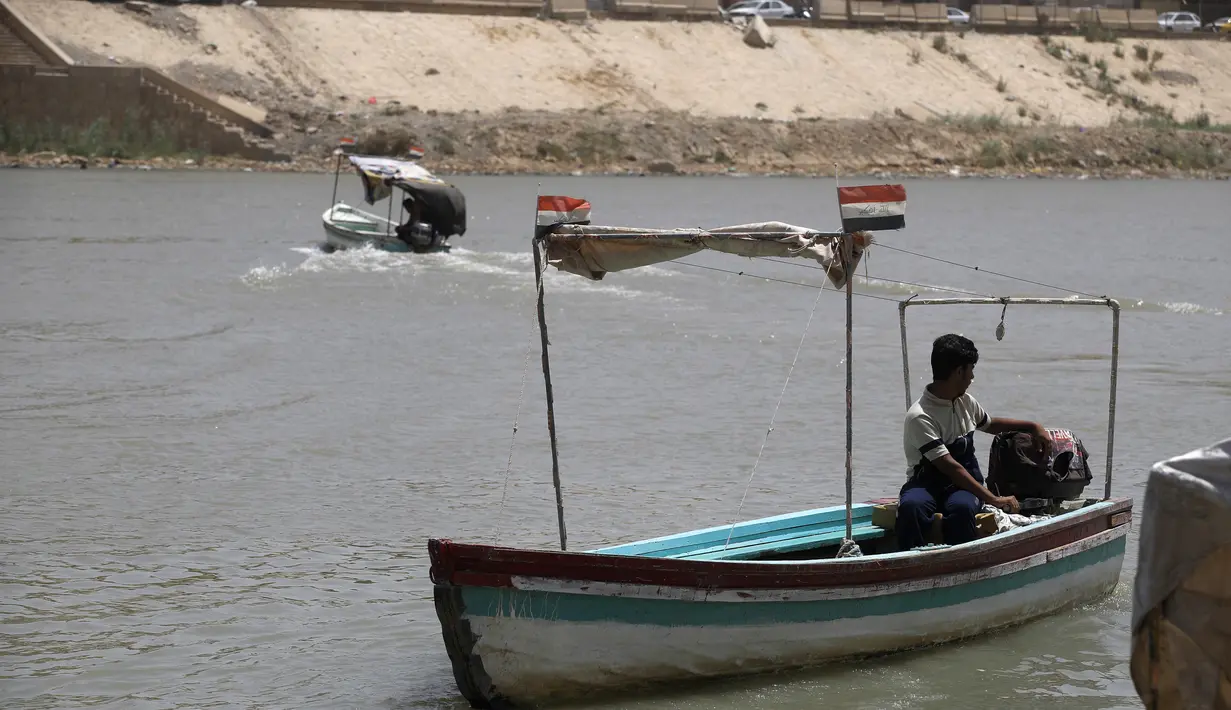 Para pria mengemudikan kapal feri kayu di sepanjang sungai Tigris saat permukaan air sungai semakin dangkal, di pusat ibu kota Irak, Baghdad, pada 26 Mei 2022. Ketinggian air di dua sungai utama Irak telah menurun secara signifikan dalam beberapa tahun terakhir, menjadi tantangan besar yang dihadapi negara semi-gurun berpenduduk 41 juta jiwa itu. (AHMAD AL-RUBAYE/AFP)