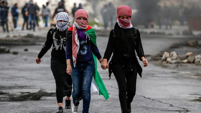 Wanita Palestina berjalan selama bentrokan dengan tentara Israel dalam demonstrasi untuk memperingati Hari Tanah di Tepi Barat, Sabtu (30/3).(Photo by ABBAS MOMANI/AFP)